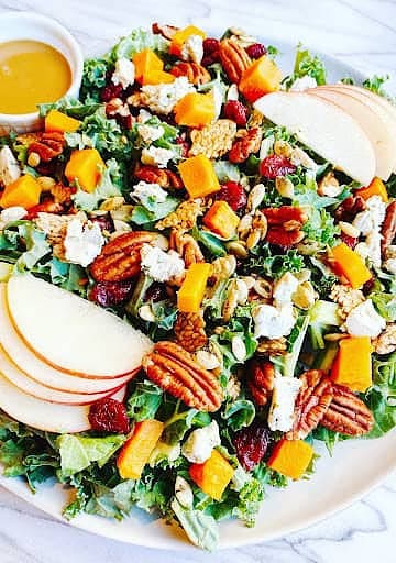 Fresh kale salad with butternut squash, cranberries, goat cheese, pecans, and a honey vinaigrette. Perfect for healthy, seasonal eating.
