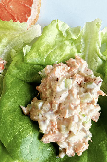 Grapefruit slices with lettuce and salmon salad on fresh green leaves, healthy seafood salad and citrus fruit appetizer, light nutritious meal.