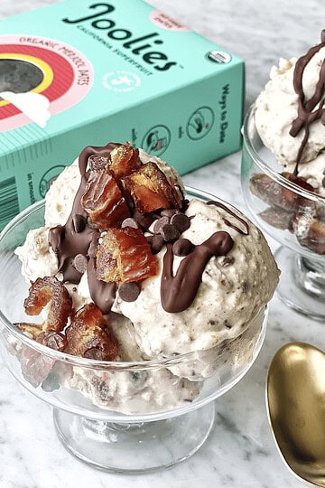 Toffee chocolate chip ice cream in glass bowls with gold spoons, featuring Lesswithlaur branding, on a marble surface.