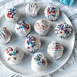 Festive red, white, and blue cake balls decorated with sprinkles for July 4th celebrations.
