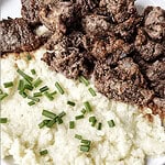 Savory beef stew with mashed potatoes and chopped green onions, comfort food recipe.