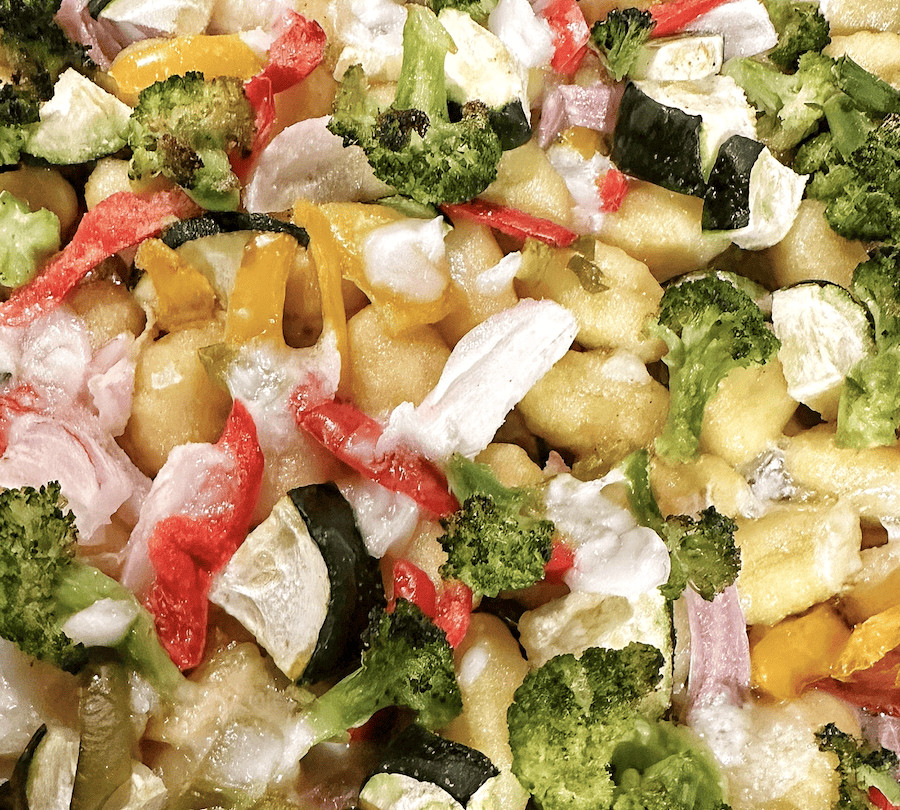 Fresh colorful vegetable pasta salad with broccoli, zucchini, red and yellow bell peppers, and mozzarella cheese. Perfect for healthy eating.