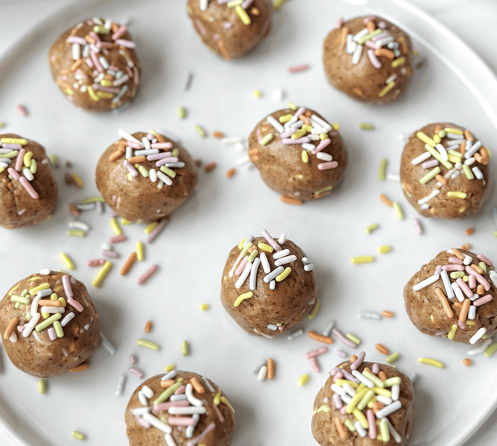 Mini chocolate energy bites with colorful sprinkles on a white plate.