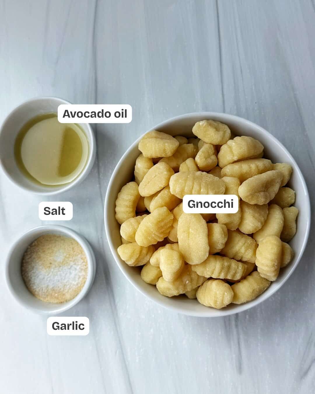 ingredients for air fryer gnocchi including gnocchi, avocado oil, salt and garlic in bowls 