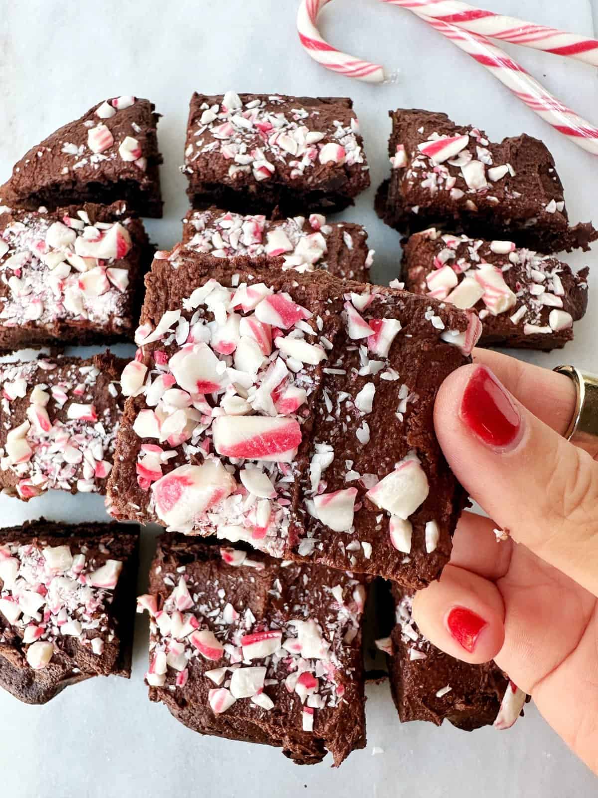 Fluffy chocolate cake batter in a white mixing bowl on white surface with candy canes for holiday baking.
