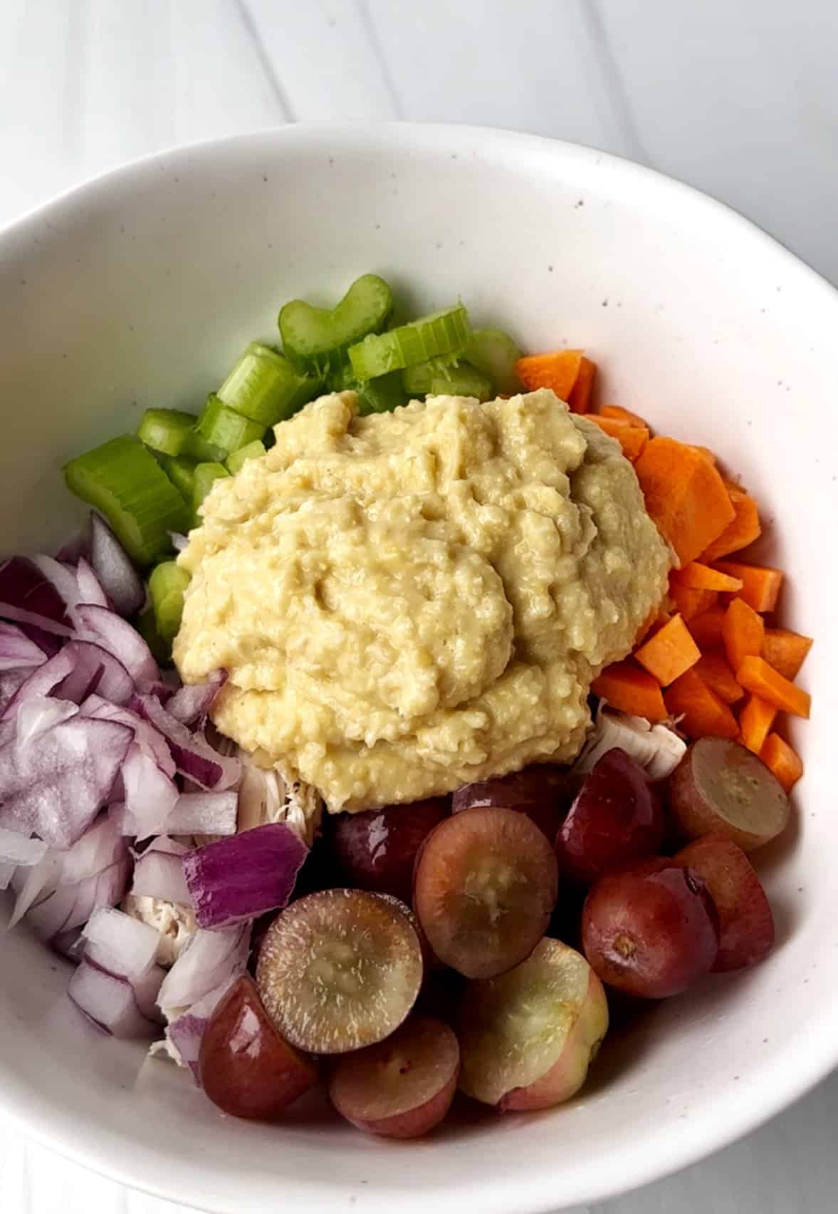 Creamy mashed potatoes with chopped celery, carrots, red onions, and grapes for healthy meal options.