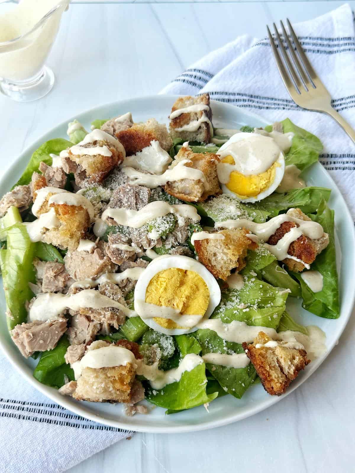 Crispy chicken salad with boiled eggs, fresh greens, croutons, and creamy dressing. Healthy and delicious meal option.