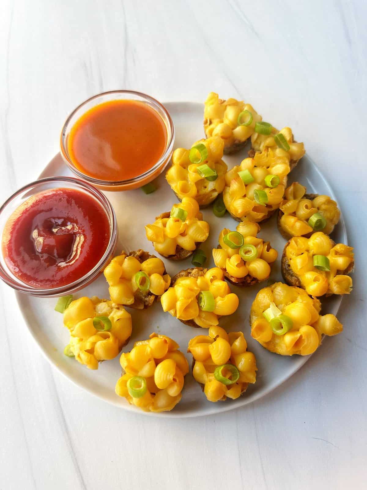 Mini cheesy corn topping appetizers with dipping sauces on a white plate.