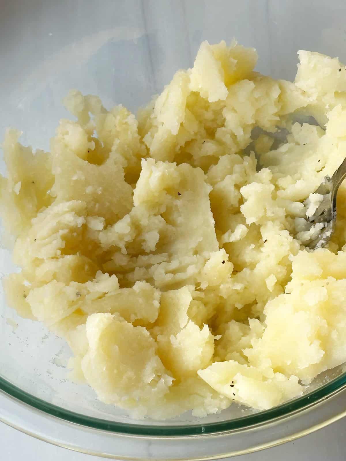 Creamy mashed potatoes in a clear glass bowl