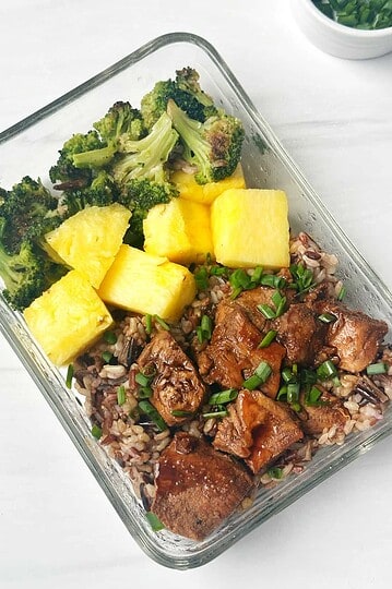 Fresh meal prep with roasted chicken, cauliflower, broccoli, and brown rice in a glass container.