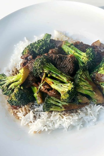 Sautéed beef and broccoli stir-fry served over white rice in a white bowl. Healthy, delicious Asian-inspired meal.