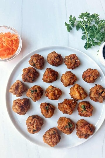 Crispy air fried chicken bites on a white plate with herbs and sauces around, healthy chicken snack, gluten-free and low carb recipe.