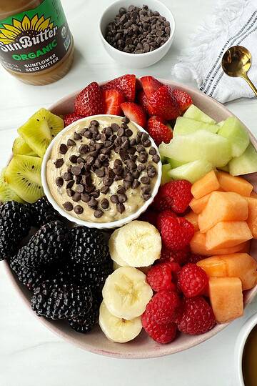 dairy-free fruit dip with chocolate chips on top on a plate with fruit