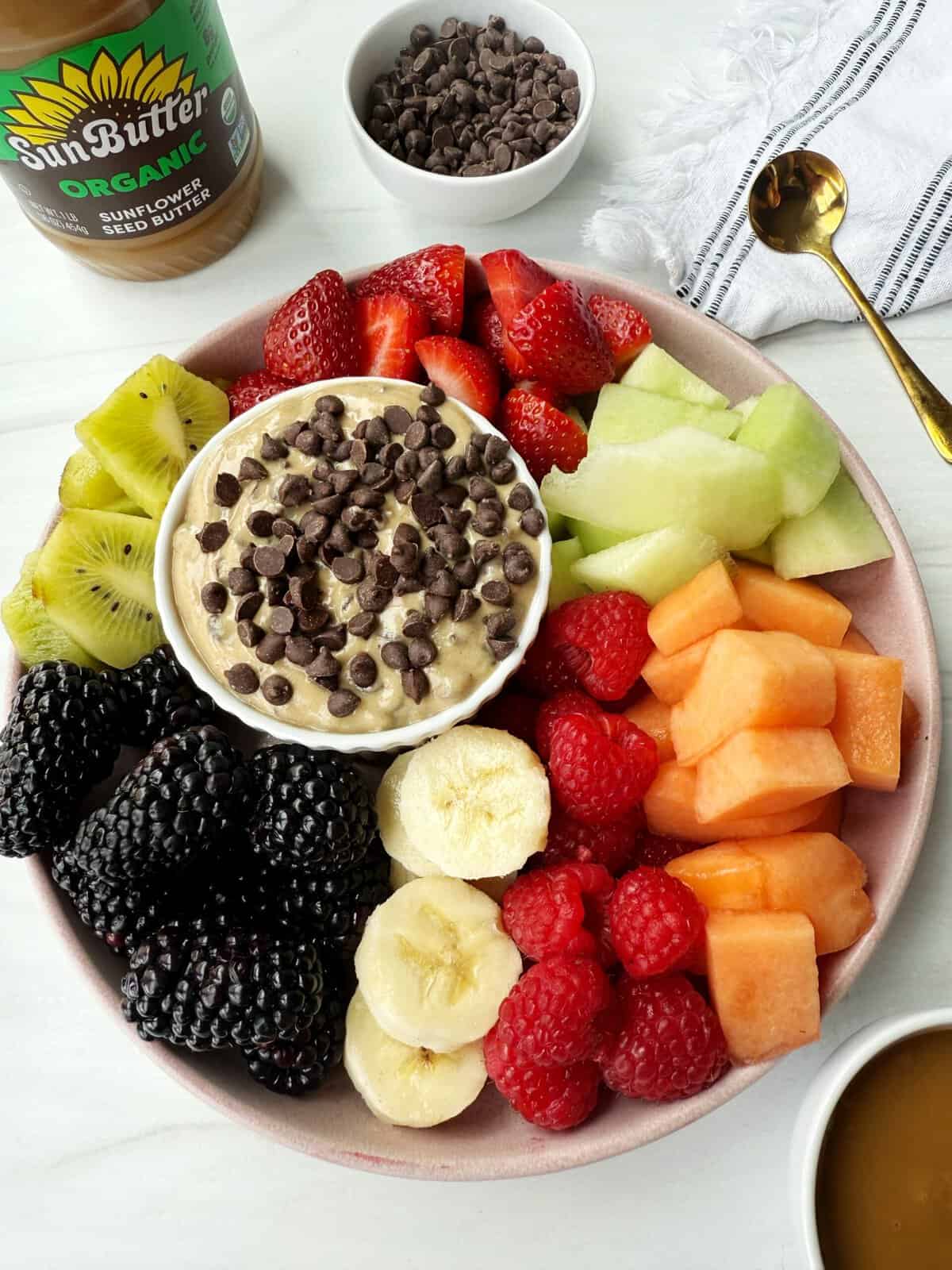 dairy-free fruit dip with chocolate chips on top on a plate with fruit