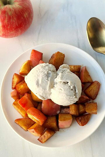 Fresh apple crumble dessert with vanilla ice cream on white plate. Healthy and sweet seasonal fruit treat. Perfect for cozy gatherings.