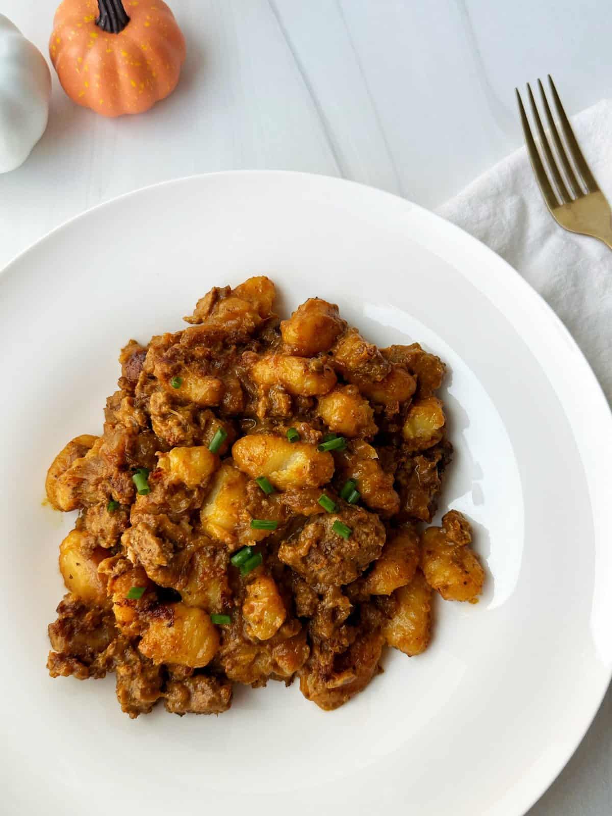 Savory pumpkin gnocchi served with sauce on a white plate