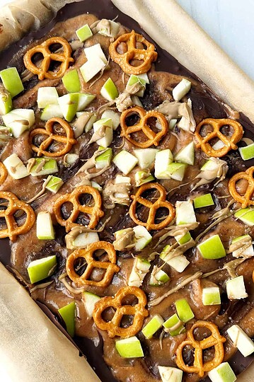 Golden brown pretzels and chopped green onions on a chocolate bark with caramel drizzle.
