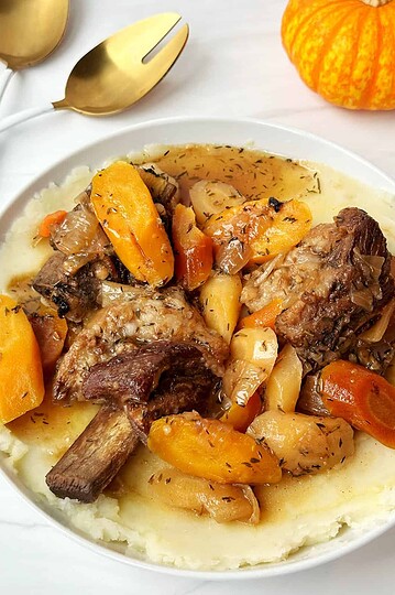 Savory beef stew served over creamy mashed potatoes with roasted vegetables. Perfect comforting fall meal.