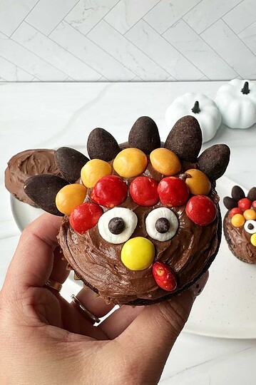 Cute reindeer-themed chocolate cupcake with colorful candy decorations.