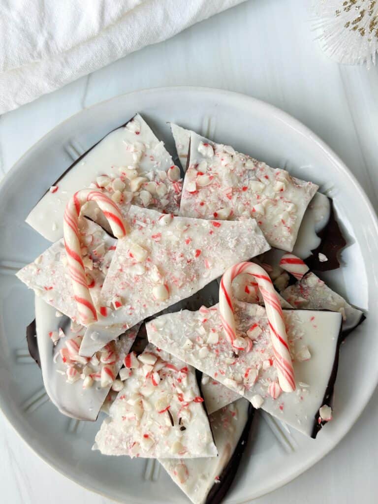 Fluffy chocolate cake batter in a white mixing bowl on white surface with candy canes for holiday baking.