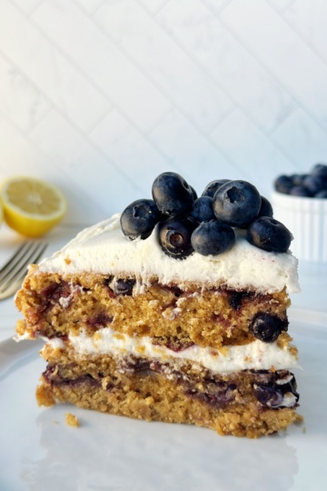 Fresh blueberry crumble cake with creamy frosting and lemon slices in the background.