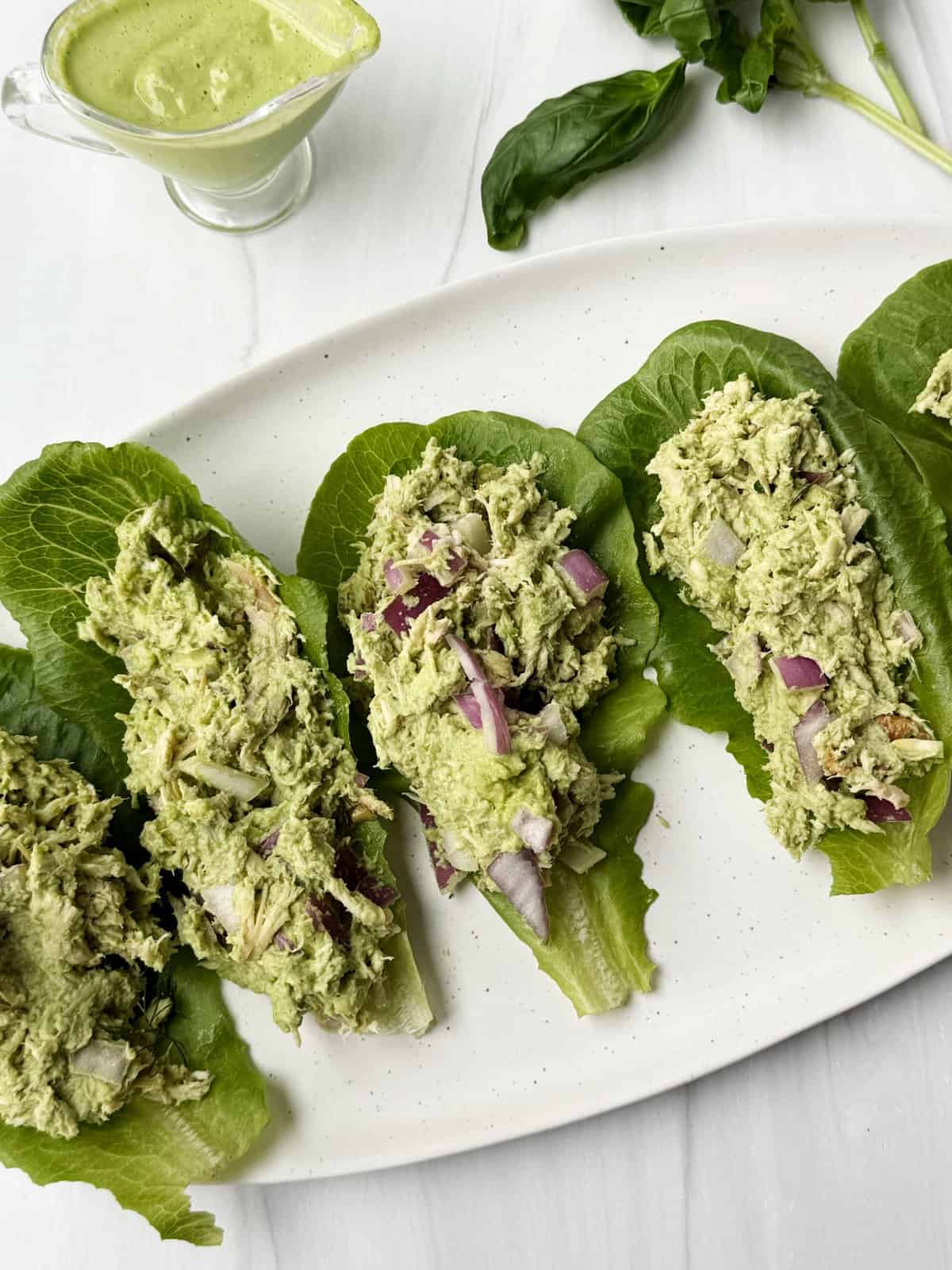 Creamy avocado tuna lettuce wraps with red onion on a white plate. Healthy, easy lunch, low-carb dinner idea.