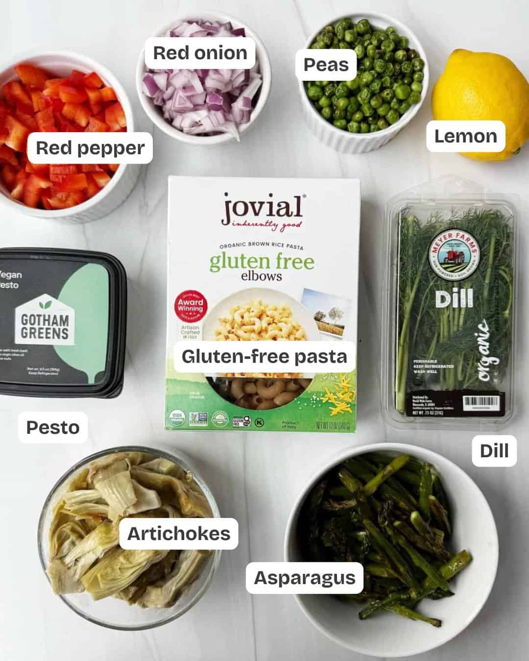 spring pasta salad ingredients including pasta, artichokes, asparagus, dill, lemon, red pepper, peas, pesto and red onion