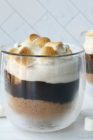 Galaxy S’mores Hot Chocolate topped with toasted marshmallows in a clear glass mug. Perfect cozy winter drink idea.