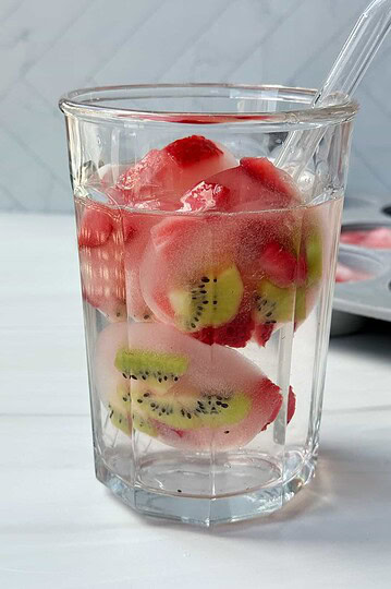Fresh fruit-infused water with slices of kiwi, strawberry, and watermelon in a clear glass.