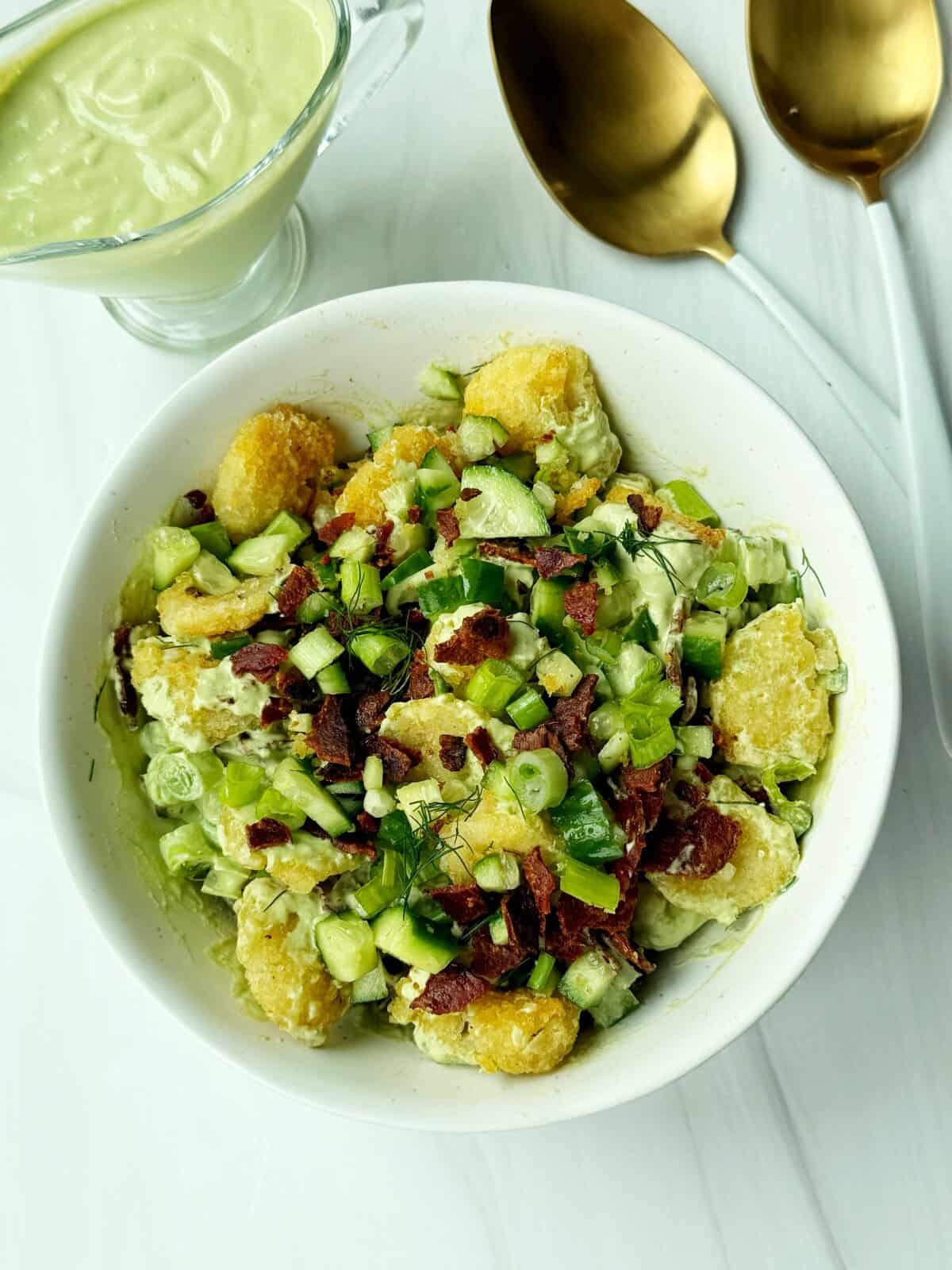 tater tot potato salad with bacon and green onions and a herby dressing on top 