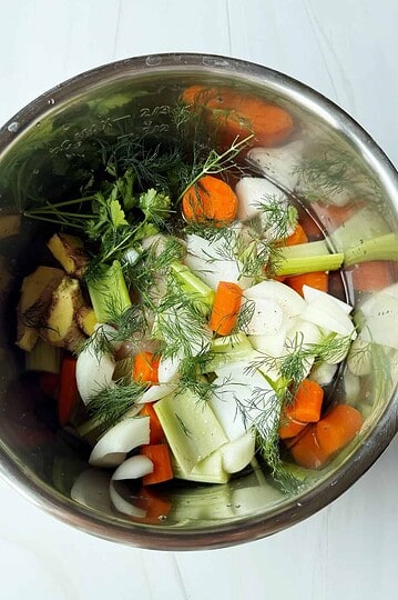 Fresh organic vegetables in a stainless steel bowl for healthy soups and meals.