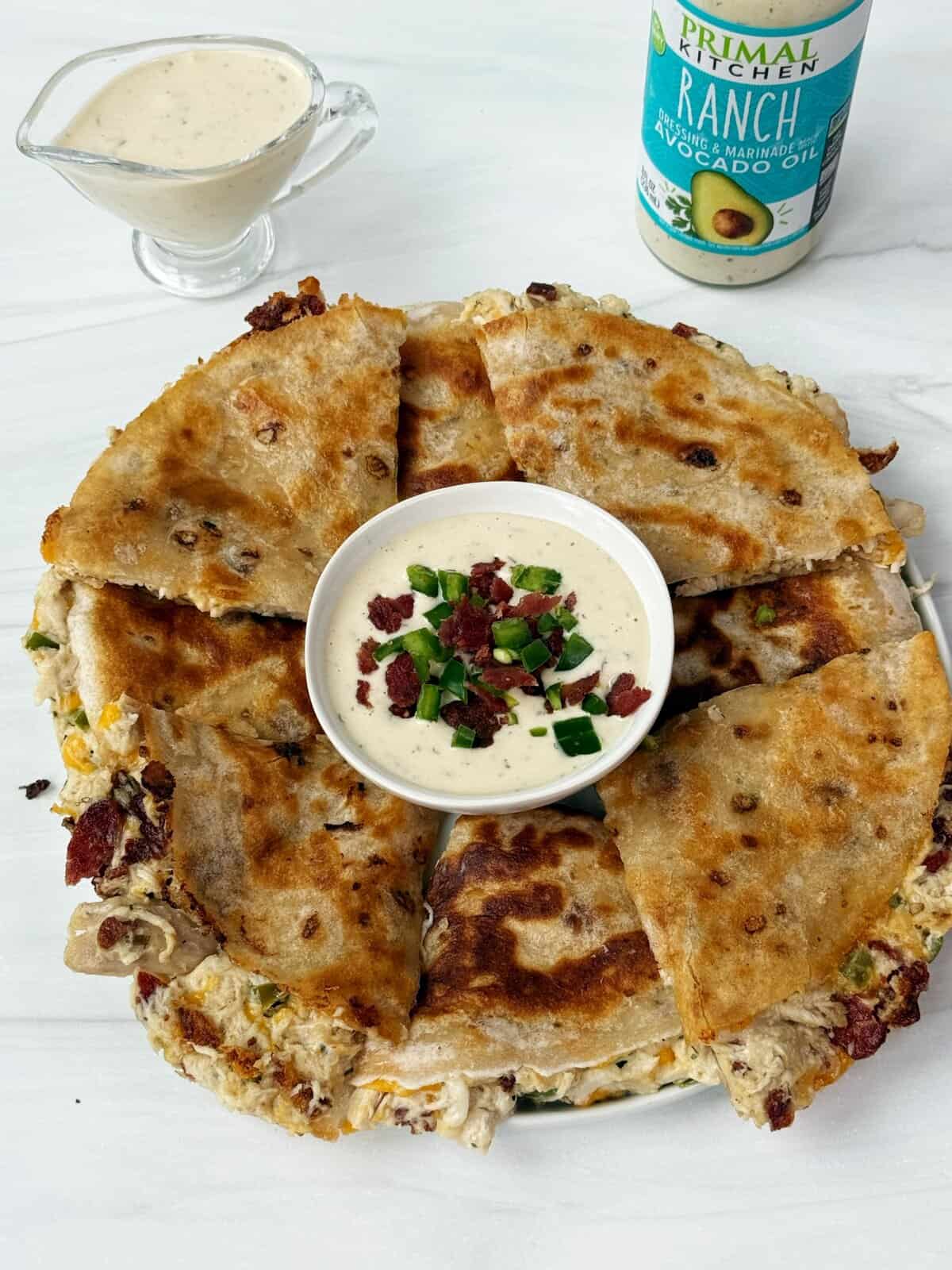 Savory breakfast quesadilla with chicken, bacon, green onions, and cheese, served with ranch sauce.