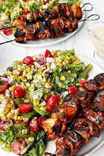 Grilled chicken skewers with barbecue sauce served with fresh summer salad.