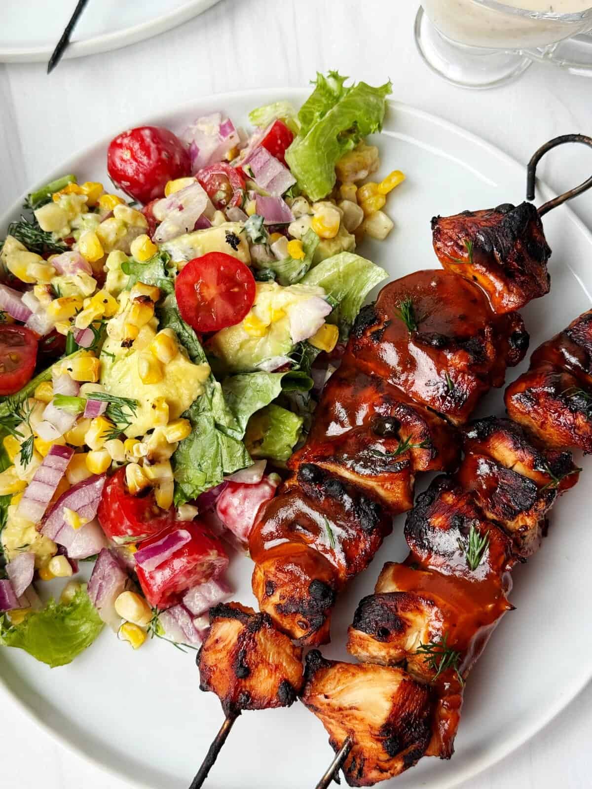 Grilled chicken skewers with barbecue sauce served with fresh vegetable garden salad.