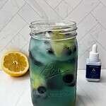 Refreshing berry lemon infused water in a glass jar with fresh fruit slices on white background.