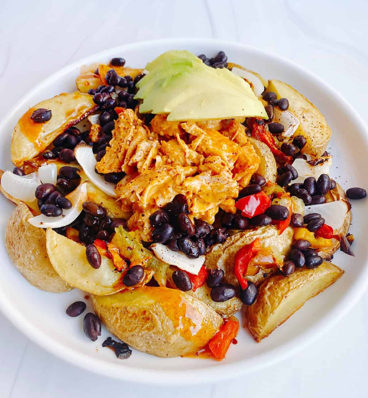 potato nachos layered with beans, vegetables and avocad
