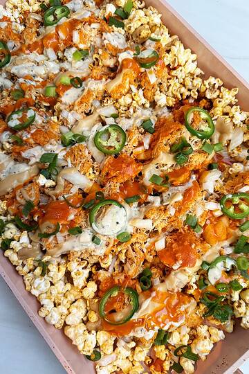 buffalo popcorn nachos on a sheet pan with toppings