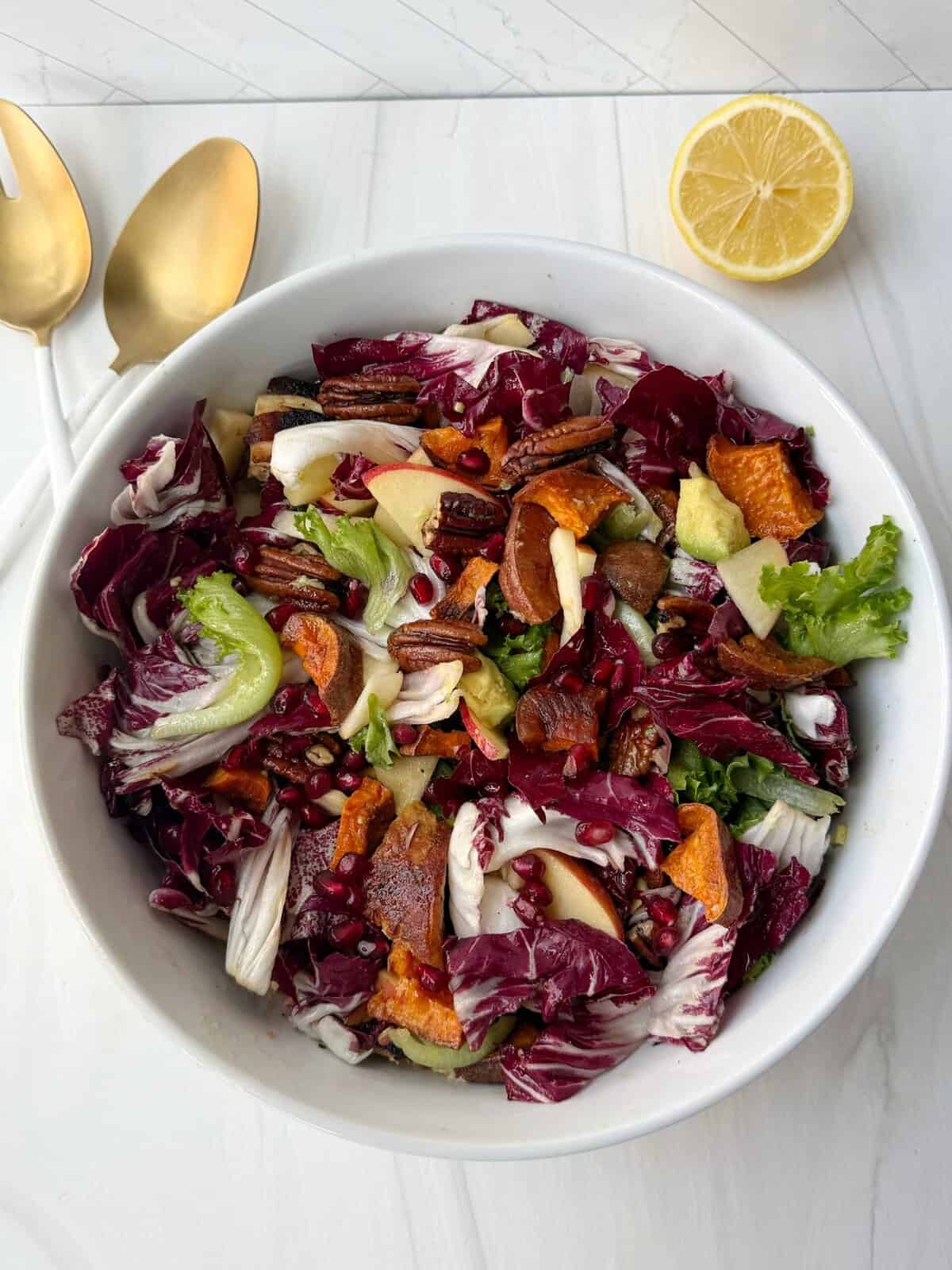 winter salad with greens, sweet potato, pomegranate seeds, avocado in a bowl