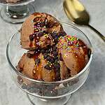 chocolate protein Ninja Creami ice cream scooped in a cup with chocolate chips and sprinkles