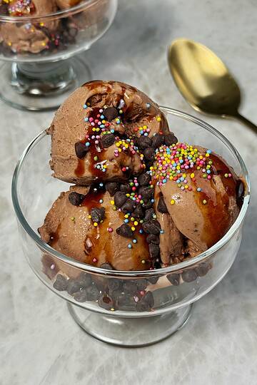 chocolate protein Ninja Creami ice cream scooped in a cup with chocolate chips and sprinkles