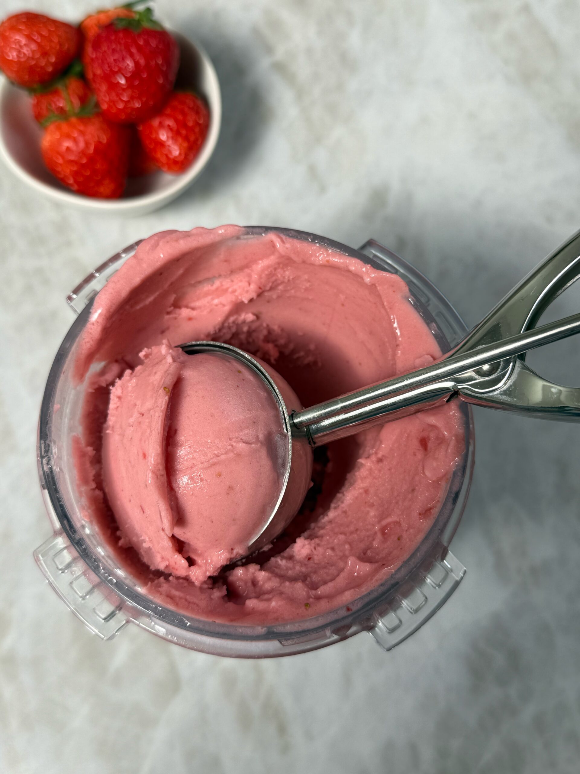 scooping ninja creami strawberry ice cream with an ice cream scoop