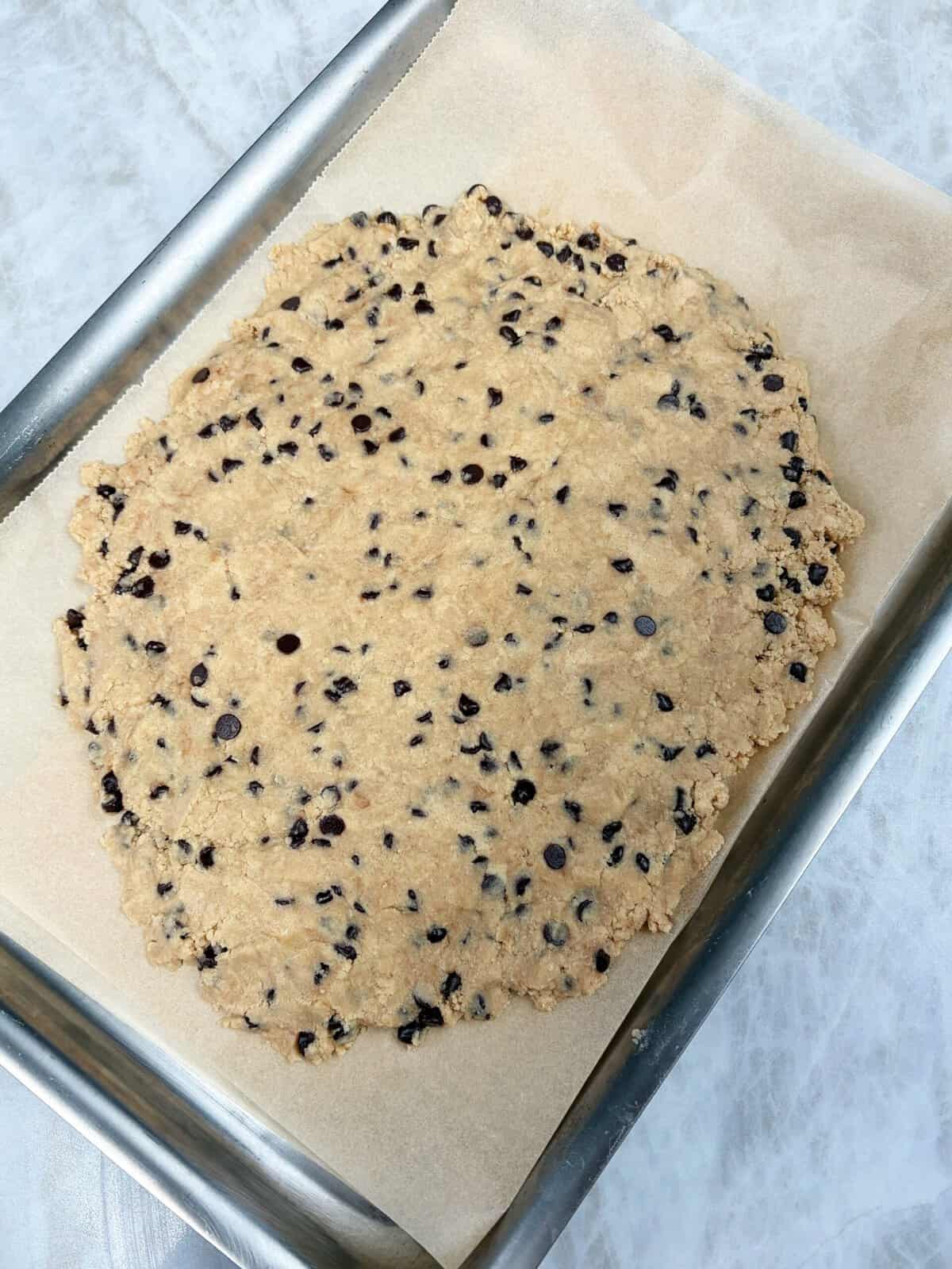 protein cookie dough pressed onto a baking sheet 