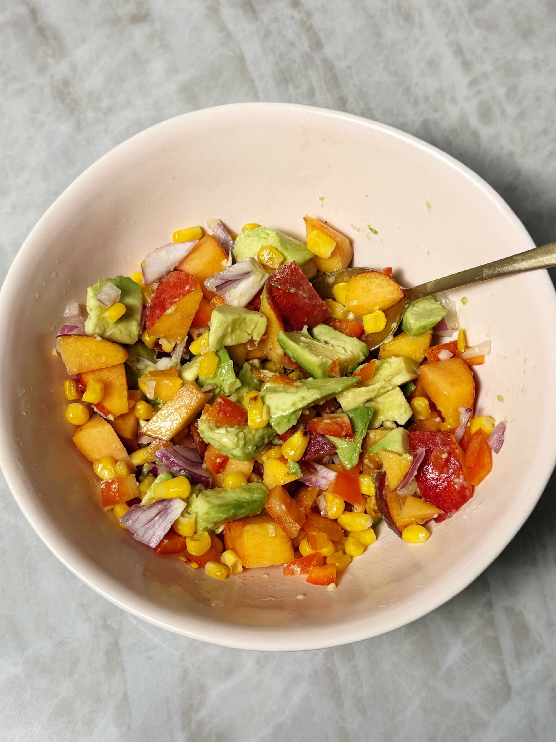 peach salsa with avocado, corn, onion in a bowl 