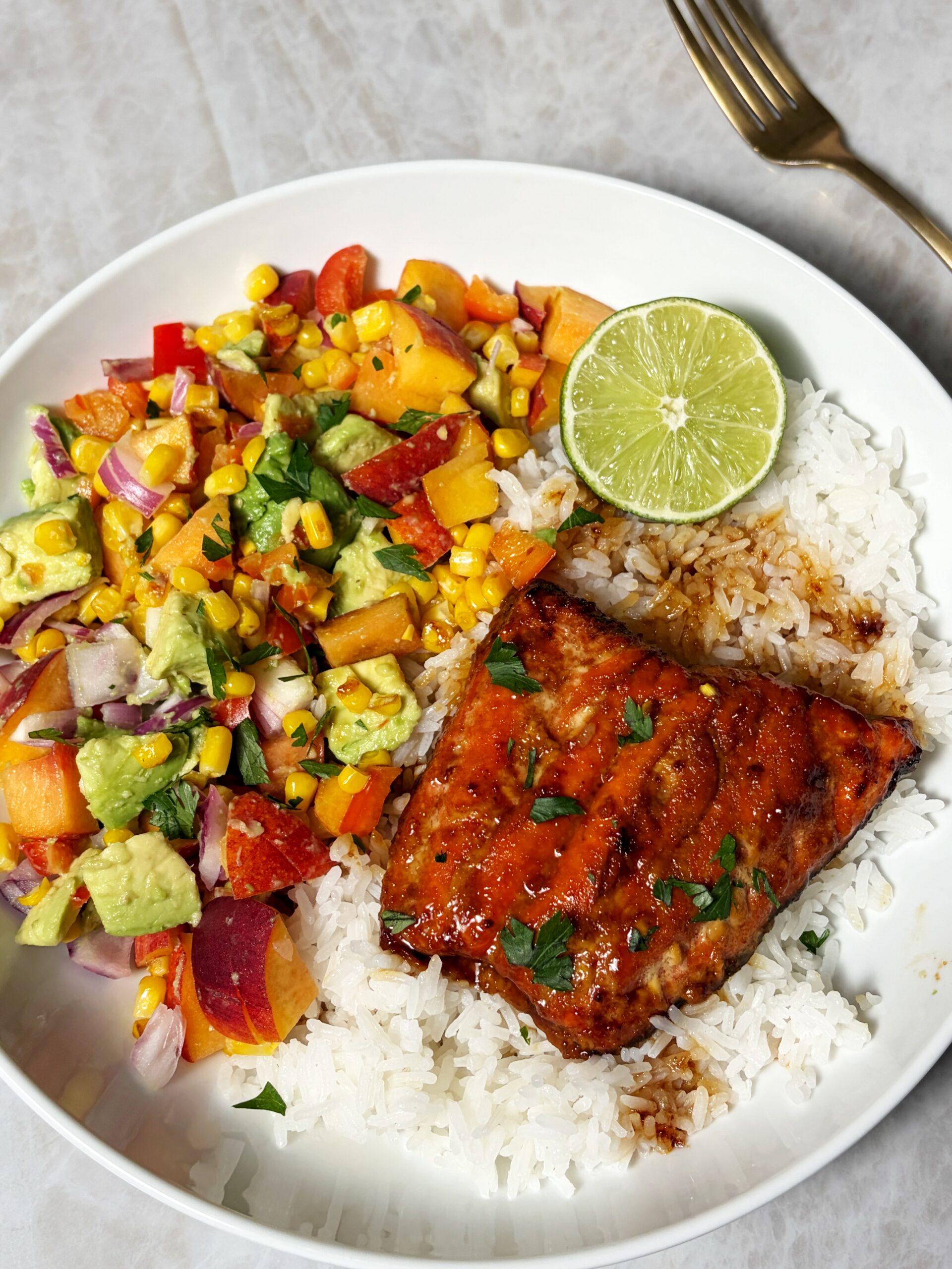 salmon with peach corn salsa over a bed of coconut rice with a lime 